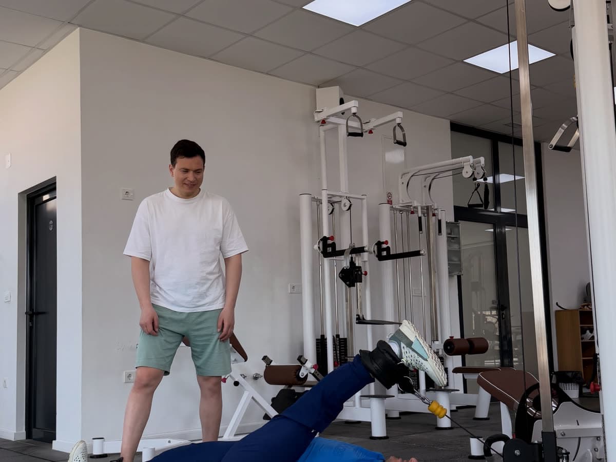 A therapist supervising floor exercises in a daylit gym